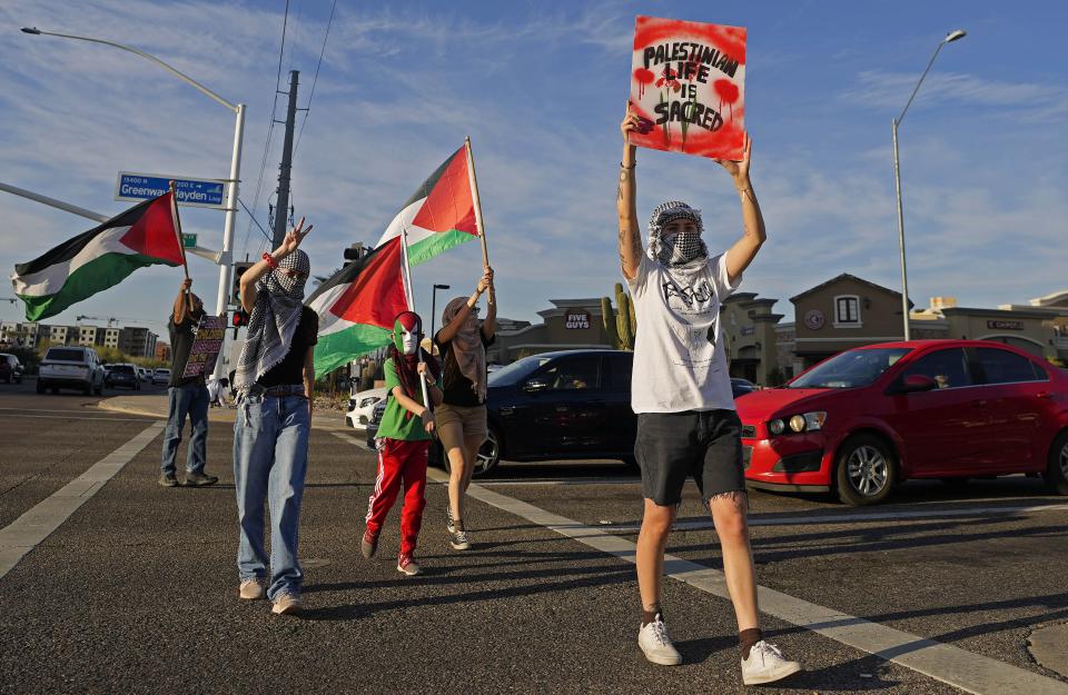 A woman identifying herself as "M" leads the group across Greenway-Hayden Loop during a Free Palestine protest at the corner of Scottsdale Road and Greenway-Hayden Loop on March 22, 2024.