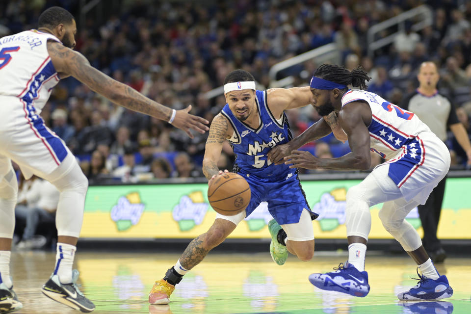 Orlando Magic guard Cole Anthony, center, drives to the basket as Philadelphia 76ers forward Marcus Morris Sr. (5) and guard Patrick Beverley, right, defend during the first half of an NBA basketball game, Friday, Jan. 19, 2024, in Orlando, Fla. (AP Photo/Phelan M. Ebenhack)