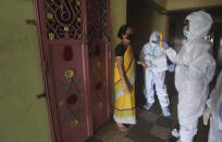 Health workers screen people for COVID-19 symptoms at a residential building in Dharavi , one of Asia's biggest slums, in Mumbai, India, Friday, Aug. 7, 2020. As India hit another grim milestone in the coronavirus pandemic on Friday, crossing 2 million cases and more than 41,000 deaths, community health volunteers went on strike complaining they were ill-equipped to respond to the wave of infection in rural areas. (AP Photo/Rafiq Maqbool)