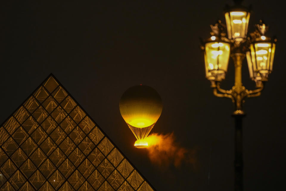 La llama olímpica se eleva en un globo aerostático tras ser encendida en París, el viernes 26 de julio de 2024 (AP Foto/Francisco Seco)