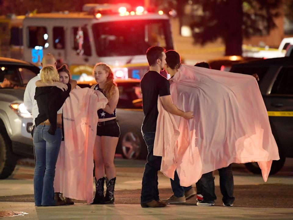 People comfort each other outside scene of shooting.