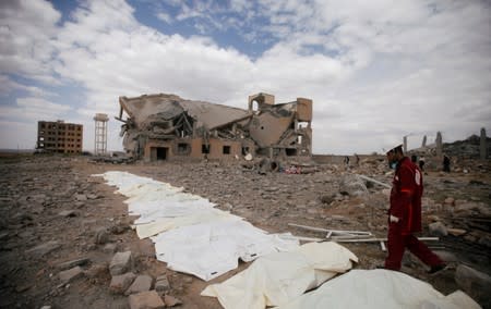 A Red Crescent medic walks next to bags containing the bodies of victims of Saudi-led airstrikes on a Houthi detention centre in Dhamar