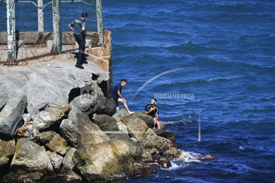 Un ufficiale della Guardia Civile spagnola accanto a un gruppo di uomini provenienti dal Marocco che stanno cercando di attraversare il confine a Ceuta.