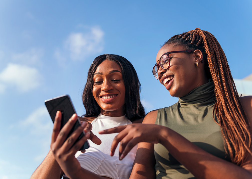 Two women talking about what they see on their phone.