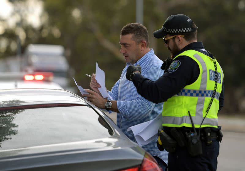 Motorists fill out paperwork for police as they cross back into South Australia from Victoria during the coronavirus disease (COVID-19) outbreak, in Bordertown