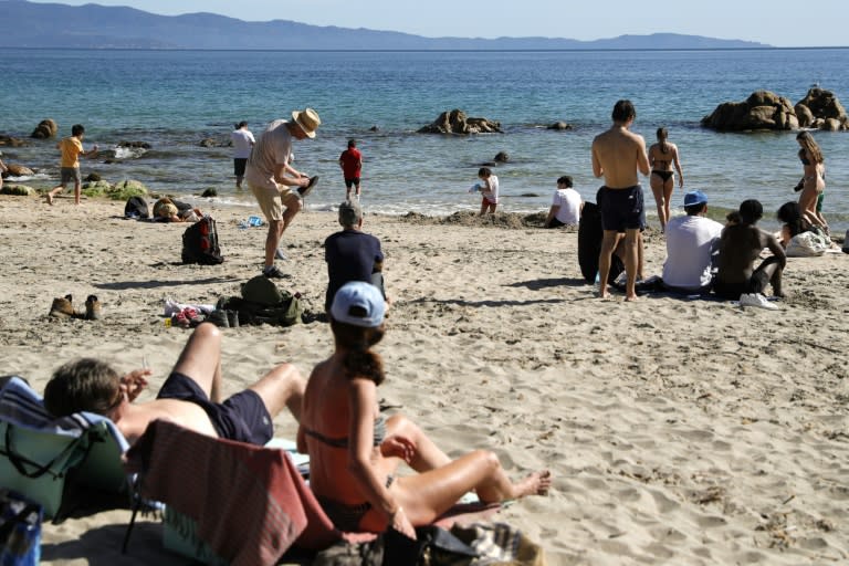 Les gens profitent de la plage avec des températures anormalement élevées pour la saison sur la plage de Terre Sacrée à Ajaccio, en Corse, le 6 avril 2024 (Pascal POCHARD-CASABIANCA)