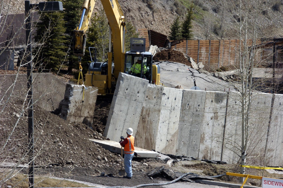 A work crew moves a concrete barrier that failed to stop a slow-motion landslide in Jackson, Wyo., as houses and businesses in the slide zone remained at risk on Saturday, April 19, 2014. No one can say when the mountainside collapsing into this Wyoming resort town will give way. But it appears increasingly likely that when it does, it's going to take a piece of Jackson with it. (AP Photo/Matthew Brown)