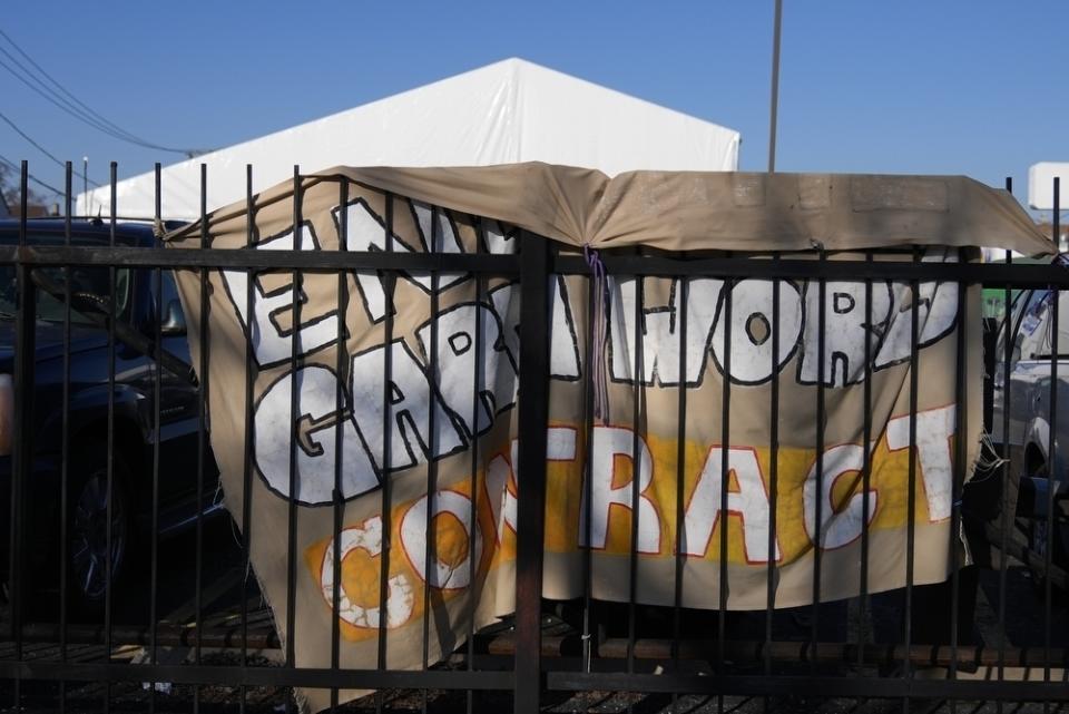 A sign reading "End the GardaWorld Contract" is posted at the site of a tent shelter built for migrants in the parking lot of an old CVS store, Thursday, Feb. 1, 2024, in the Little Village neighborhood of Chicago. GardaWorld is the security firm hired by the city to build shelters. (AP Photo/Erin Hooley) oley)