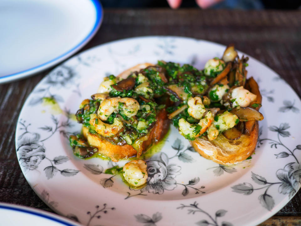 Shrimp and vegetables on toasted bread, served on a floral plate