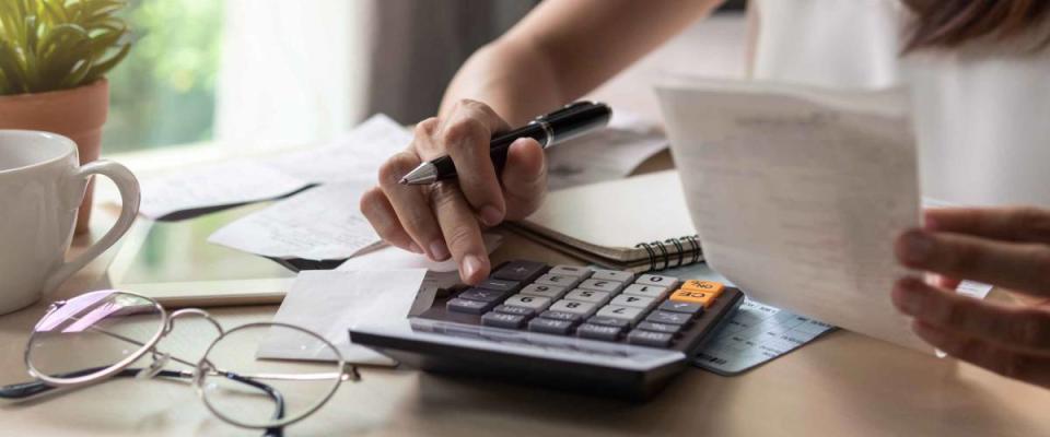 Stressed young woman checking bills, taxes, bank account balance and calculating expenses in the living room at home