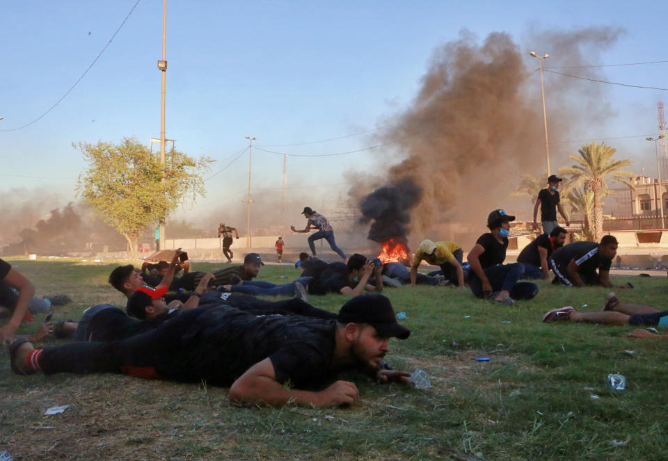 Anti-government protesters take cover while Iraq security forces fire during a demonstration in Baghdad, Iraq, Friday, Oct. 4, 2019. Security forces opened fire directly at hundreds of anti-government demonstrators in central Baghdad, killing several protesters and injuring dozens, hours after Iraq's top Shiite cleric warned both sides to end four days of violence "before it's too late." (AP Photo/Khalid Mohammed)