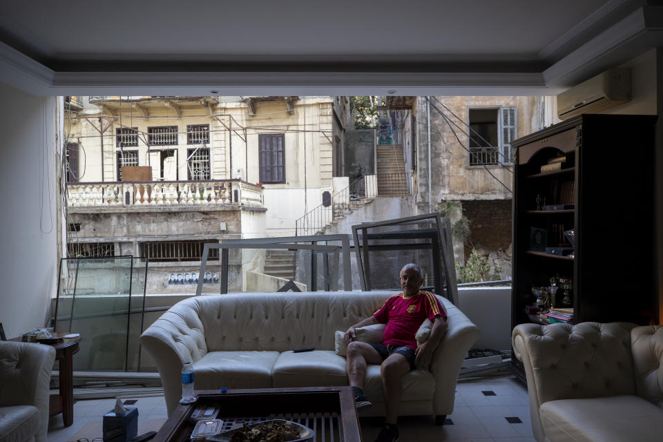 George Abdo, 58, poses for a photograph inside his destroyed apartment after Tuesday's explosion in the seaport of Beirut, Lebanon, Thursday, Aug. 6, 2020. The gigantic explosion in Beirut on Tuesday tore through homes, blowing off doors and windows, toppling cupboards, and sent flying books, shelves, lamps and everything else. Within a few tragic seconds, more than a quarter of a million people of the Lebanese capital's residents were left with homes unfit to live in. Around 6,200 buildings are estimated to be damaged. (AP Photo/Hassan Ammar)