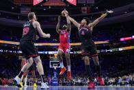 Philadelphia 76ers' James Harden (1) goes up for a shot against Toronto Raptors' Jakob Poeltl (19) and Scottie Barnes during the first half of an NBA basketball game, Friday, March 31, 2023, in Philadelphia. (AP Photo/Matt Rourke)