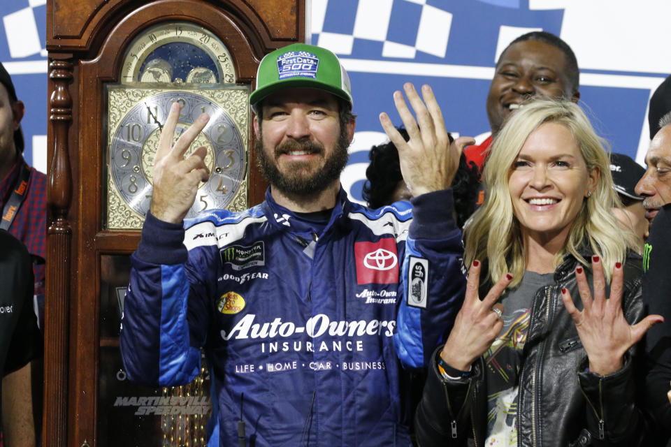 Martin Truex Jr., left, and his girlfriend Sherry Pollex, right, pose with the trophy as he celebrates after winning a NASCAR Cup Series race at Martinsville Speedway in Martinsville, Va., Sunday, Oct. 27, 2019. (AP Photo/Steve Helber)