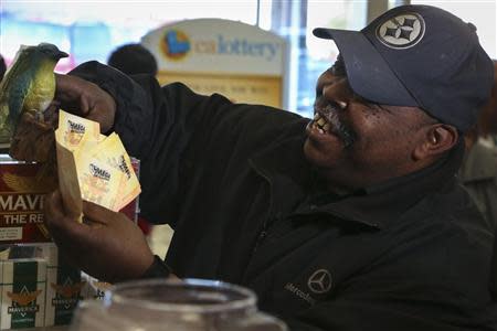 Aubrey Murray rubs his Mega Millions lottery tickets on a good luck bird statuette at Bluebird Liquor in Hawthorne, California December 13, 2013. REUTERS/Jonathan Alcorn