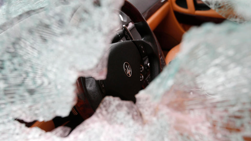 A close-up of a Maserati with shattered windows.