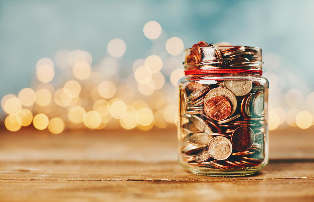  Donation money jar filled with coins in front of holiday lights. 