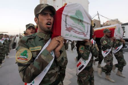 Members of the Shi'ite militia Asaib Ahl al-Haq carry coffins of fighters from their group who were killed during clashes with militants of the Islamic State, formerly known as the Islamic State of Iraq and the Levant (ISIL), during a funeral in Najaf, in this July 7, 2014 file photo. REUTERS/Alaa Al-Marjani/Files