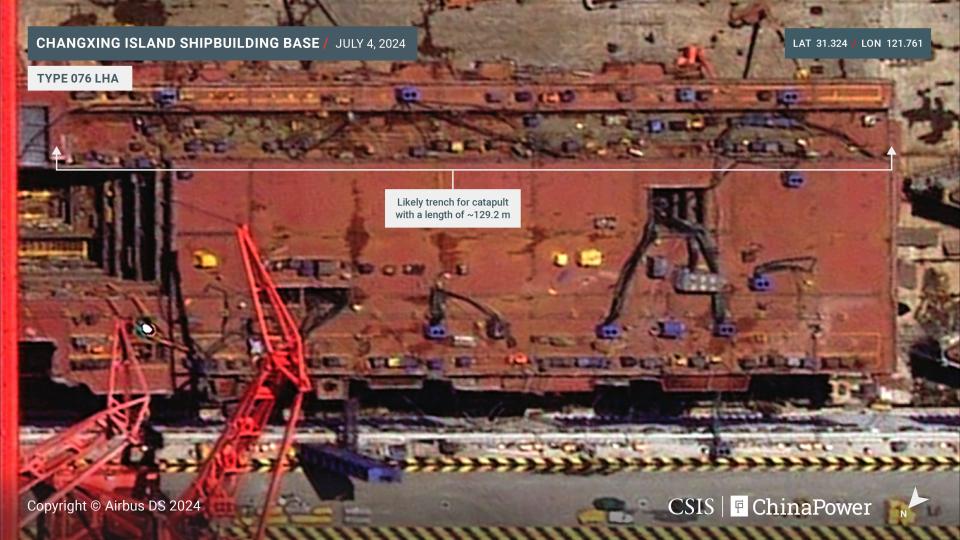 A satellite image showing China's new amphibious assault ship being built at a shipyard. There is a text overlay showing the length of the slot for launching aircraft.