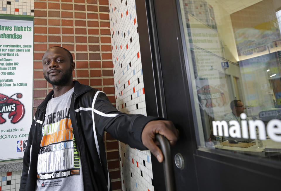 In this June 21, 2019, photo, Blaise Matshieba Nduluyele leans on a door to the Expo Center in Portland, Maine, where he and his family have been provided with temporary shelter along with hundreds of other African migrants, mostly from Congo and Angola. Blaise Nduluyele fled when an armed conflict erupted in his village in the Democratic Republic of Congo. “I really didn’t think I would survive. It was really, truly terrifying,” said Nduluyele, now safe at a shelter with his wife and three children in Maine. (AP Photo/Elise Amendola)