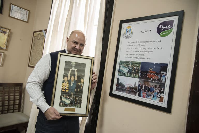 Daniel Quacquarini, presidente Comunal de Pujato, junto a una serie de fotografias que se exhiben en la comuna, del técnico de futbol, cuando se consagró campeón en el mundial juvenil de Malasia en 1997.