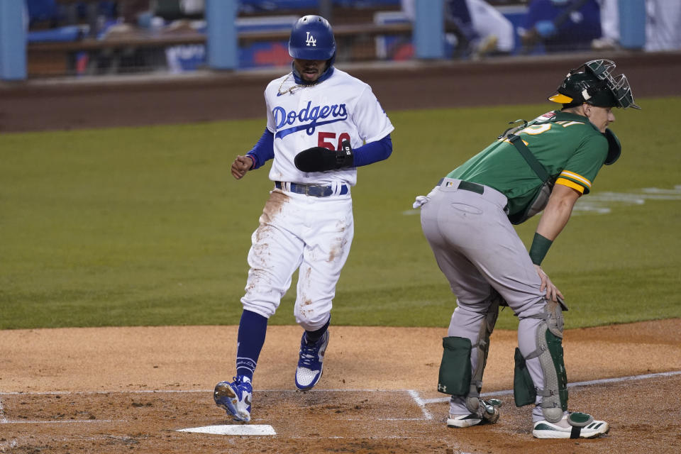 Los Angeles Dodgers' Mookie Betts scores on a single by Corey Seager during the first inning of a baseball game against the Oakland Athletics Tuesday, Sept. 22, 2020, in Los Angeles. Oakland Athletics catcher Sean Murphy is at right. (AP Photo/Ashley Landis)