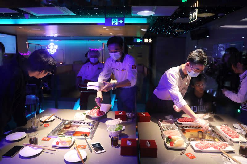 FILE PHOTO: Waiters serve customers at a Haidilao hotpot restaurant in Beijing