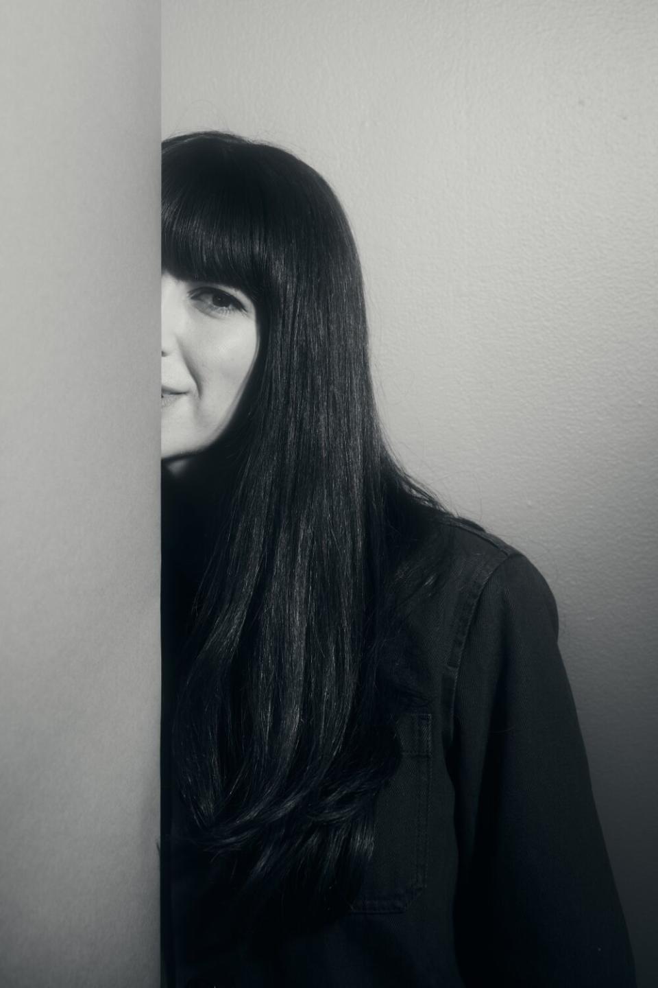 A woman peeks from behind a backdrop.