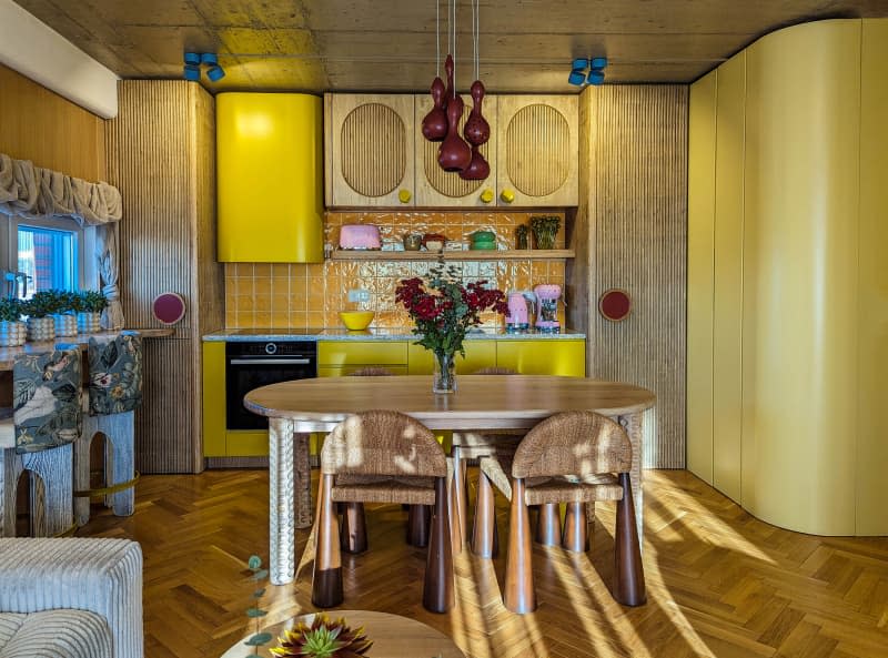 Yellow kitchen with fluted wood cabinets, parquet floor, window bar and dining table