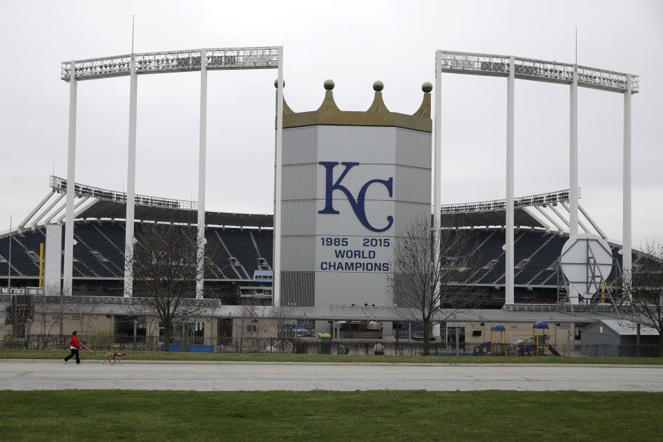 FILE - A woman and her dog walk past Kauffman Stadium, home of the Kansas City Royals baseball team, Wednesday, March 25, 2020, in Kansas City, Mo. Voter rejection of a stadium sales tax plan for the Kansas City Royals and Chiefs has raised questions about what happens next. (AP Photo/Charlie Riedel, File0