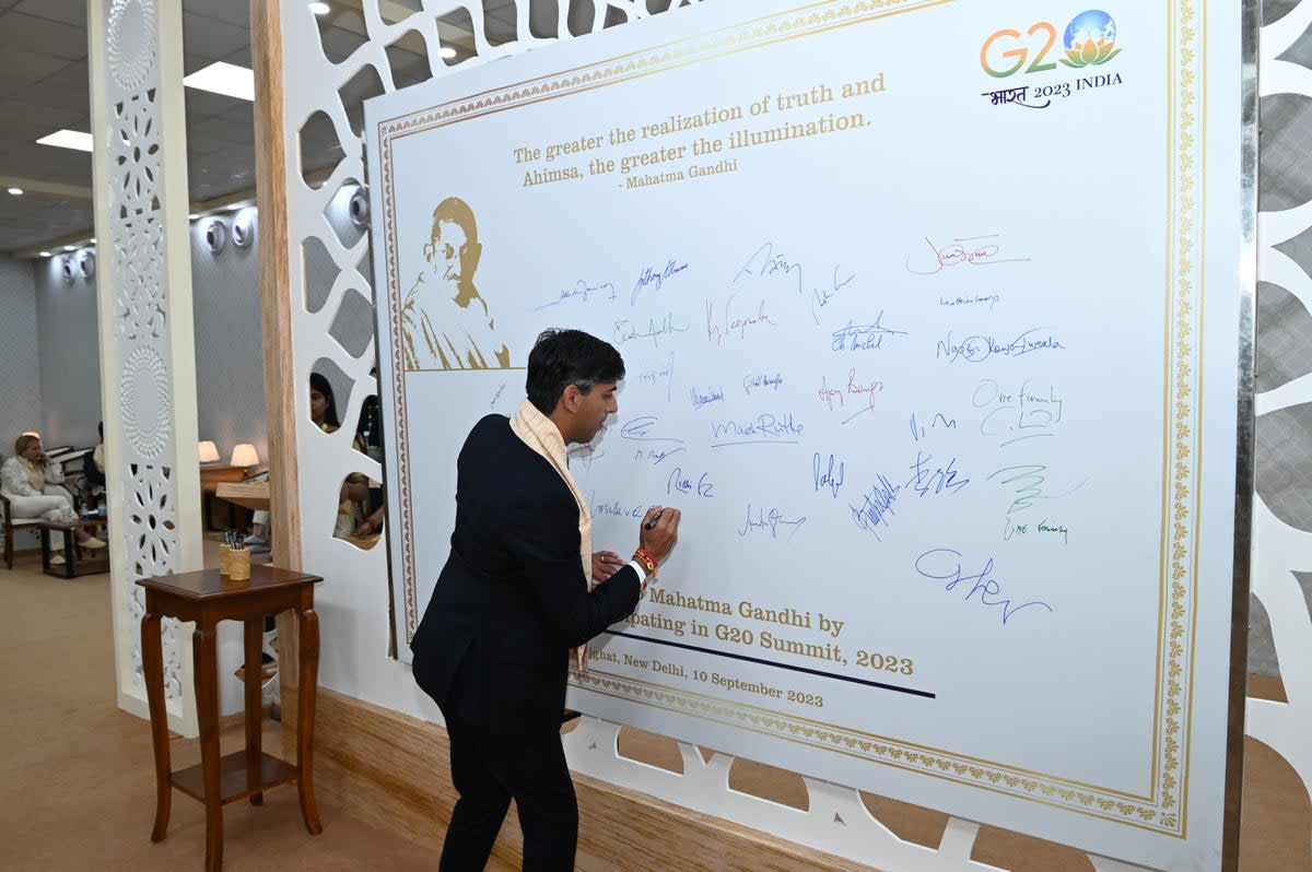 British prime minister Rishi Sunak signs the ‘Peace Wall’ at the Raj Ghat (Anadolu Agency via Getty)