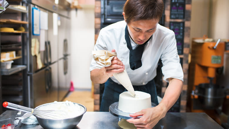 baker frosting a cake