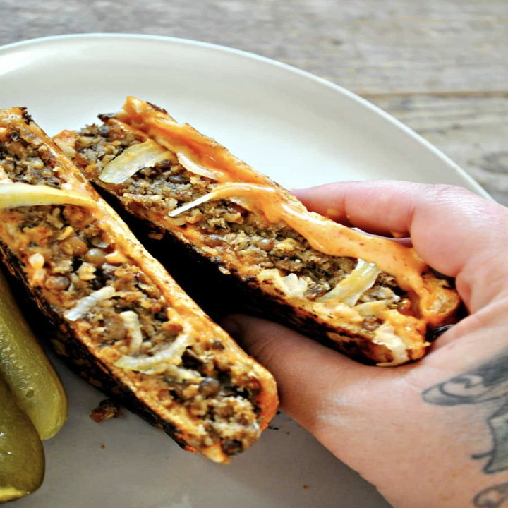 A sandwich with lentils and cheese pouring out of it