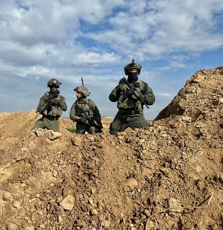 Three IDF soldiers stand over the excavated tunnel.