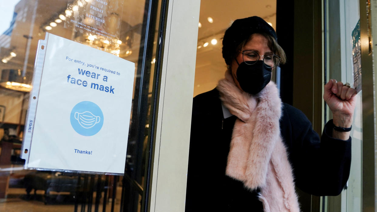 A person wearing a mask walks out of a store past a 