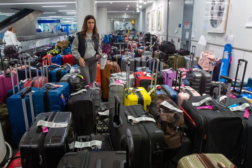 Los Angeles, CA - 27 dhjetor: Amanda Gevorgyan kërkon bagazhin e saj midis qindra bagazheve nga anulimet e fluturimeve në Jugperëndim, të mbledhura në marrjen e bagazheve në Terminalin 1 LAX Southwest të martën, 27 dhjetor 2022 në Los Angeles, CA. (Irfan Khan / Los Angeles Times)