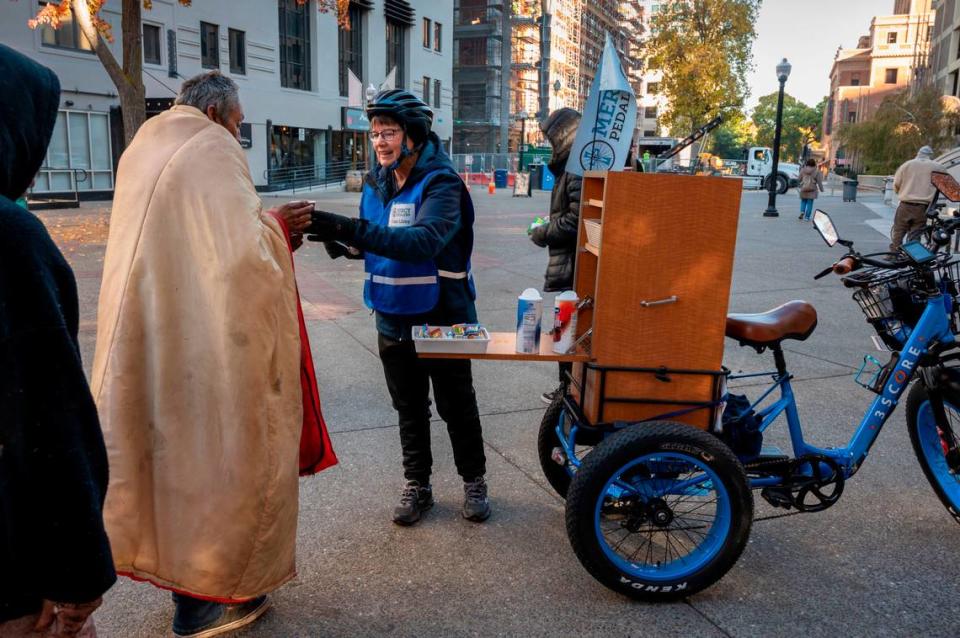 Sister Libby Fernandez with Mercy Pedalers gives out coffee and supplies to people experiencing homelessness Friday, Nov. 10, in downtown Sacramento in front of the Cathedral of the Blessed Sacrament.