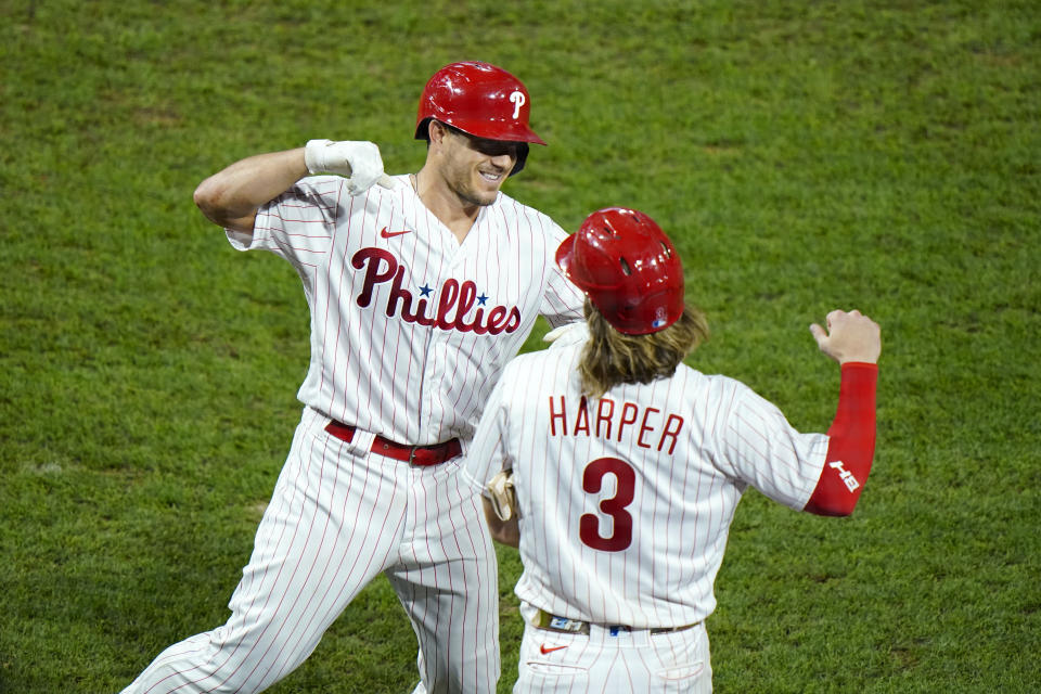 Philadelphia Phillies' J.T. Realmuto, left, and Bryce Harper celebrate after Realmuto's three-run home run off New York Mets pitcher Walker Lockett during the fifth inning of a baseball game, Friday, Aug. 14, 2020, in Philadelphia. (AP Photo/Matt Slocum)