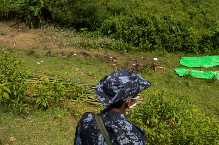 A policeman stands guard near the dead bodies of Hindu victims at Ye Baw Kyaw village, in Myanmar's northern Rakhine state in September 2017