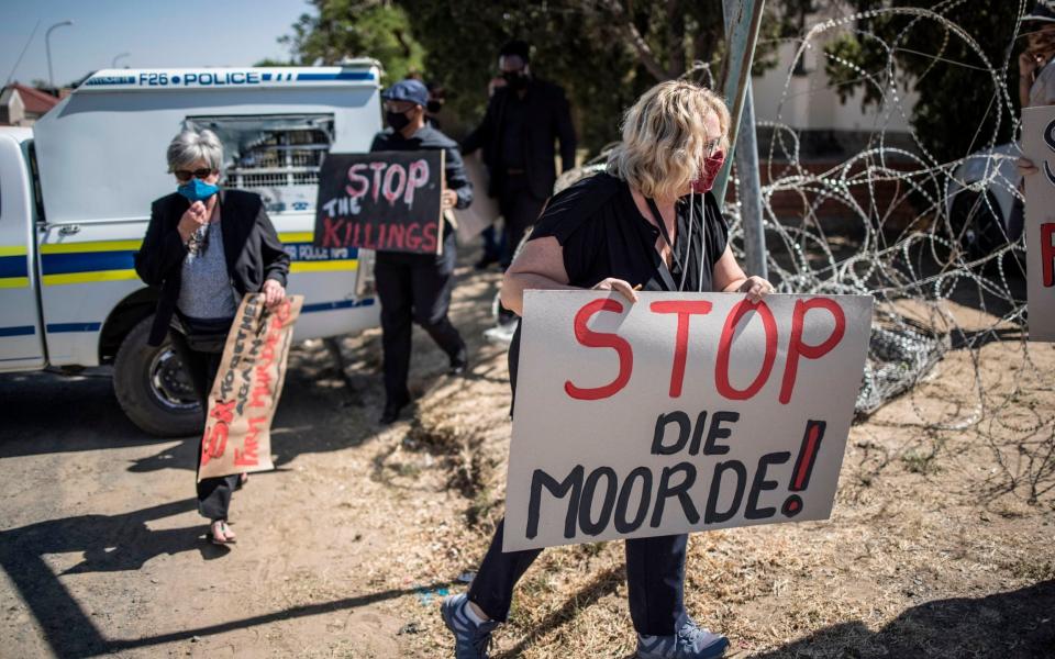 Demonstrators carry placards during a demonstration against farm attacks - AFP