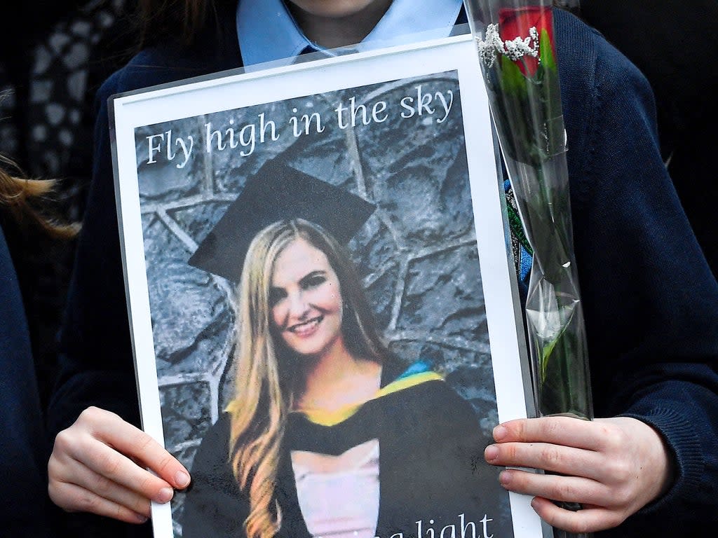 A pupil from Ashling Murphy’s class holds a photograph of her and a red rose ahead of her funeral in County Offaly (Reuters)