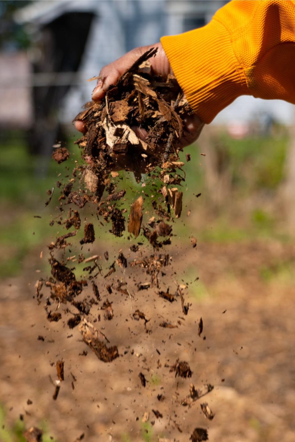 Tysha Ahmad lets mulch fall to the ground Wednesday, April 26, 2023, in Indianapolis after city crews came and cleared the lot of illegally dumped trash, taking much of the mulch in the process. 