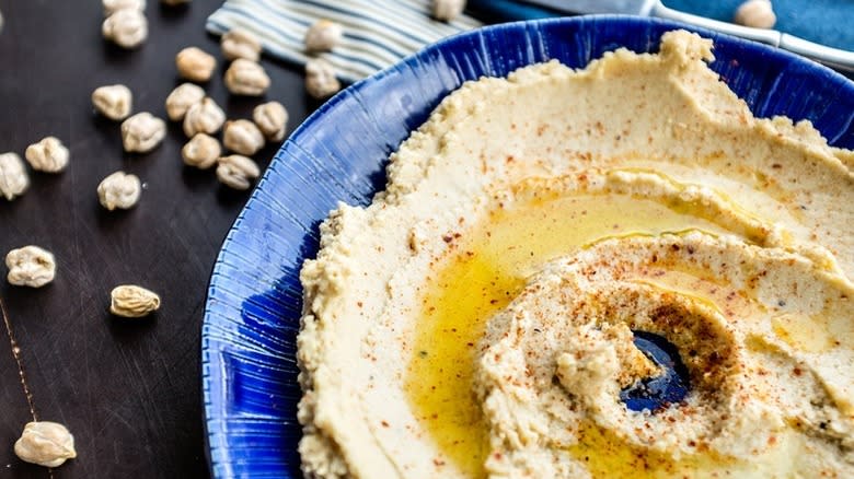 Hummus in blue serving bowl with spices and olive oil