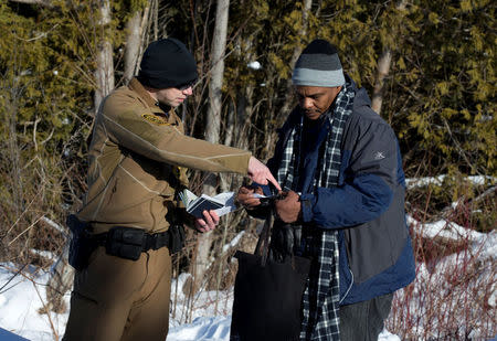 A man who claimed to be from Sudan has his and his family's passports checked by a U.S. border patrol officer at the U.S.-Canada border into Hemmingford, Canada, from Champlain in New York, U.S., February 17, 2017. REUTERS/Christinne Muschi