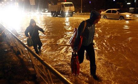 People walk along a flooded street in Sochi, September 24, 2013. REUTERS/Maxim Shemetov