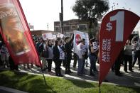 Demonstrators hold signs and banners during a protest outside a McDonald's restaurant on Tuesday, March 18, 2014, in Huntington Park, Calif. Protesters were set to rally outside McDonald's restaurants in cities including Boston, Chicago and Miami to call attention to the denial of overtime pay and other violations they say deprive workers of the money they're owed. (AP Photo/Jae C. Hong)