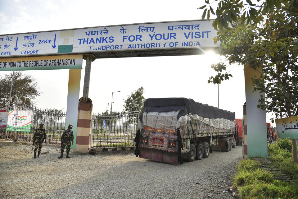 Indian Border Security Force soldiers stand guard as trucks carrying wheat from India pass through the Attari-Wagah border between India and Pakistan, near Amritsar, India, Tuesday, Feb. 22, 2022. India's foreign ministry says it has sent off tons of wheat to Afghanistan to help relieve desperate food shortages, after New Delhi struck a deal with neighboring rival Pakistan to allow the shipments across the shared border. (AP Photo/Prabhjot Gill)