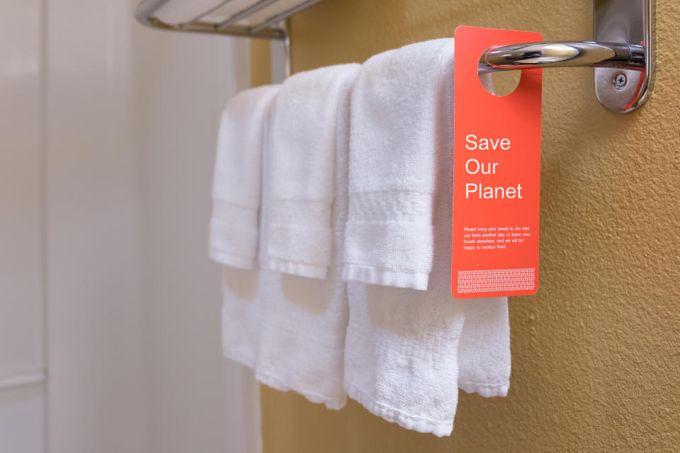 Towels hanging on a rack with a red tag that reads "Save Our Planet" urging reuse to save water and energy