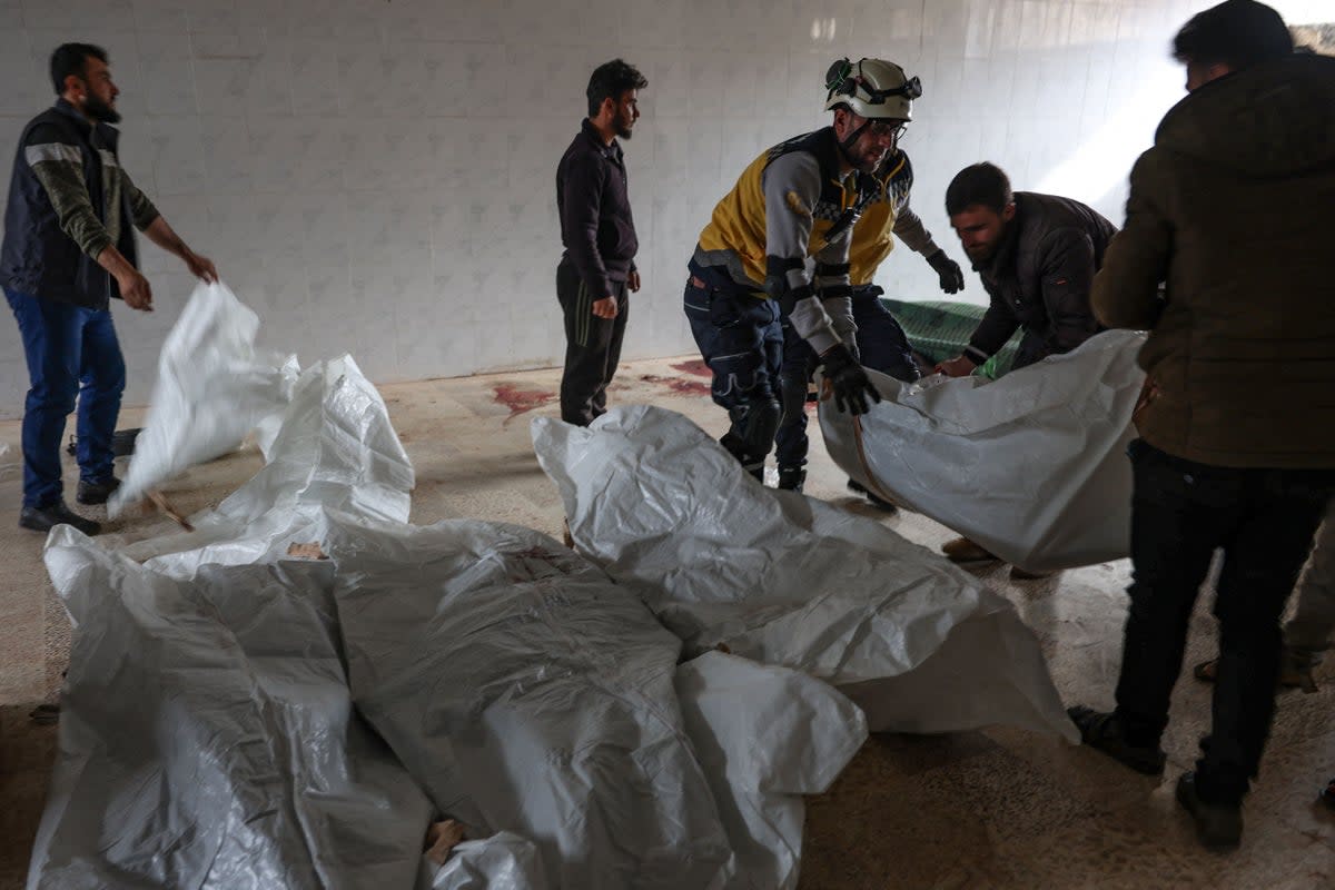 Residents and a rescuer from the Syrian White Helmets, pile up  bodies of civilians killed in a Syrian regime bombardment in the town of Kaokafin in the rebel-held Idlib province on November 25, 2023 (AFP via Getty Images)