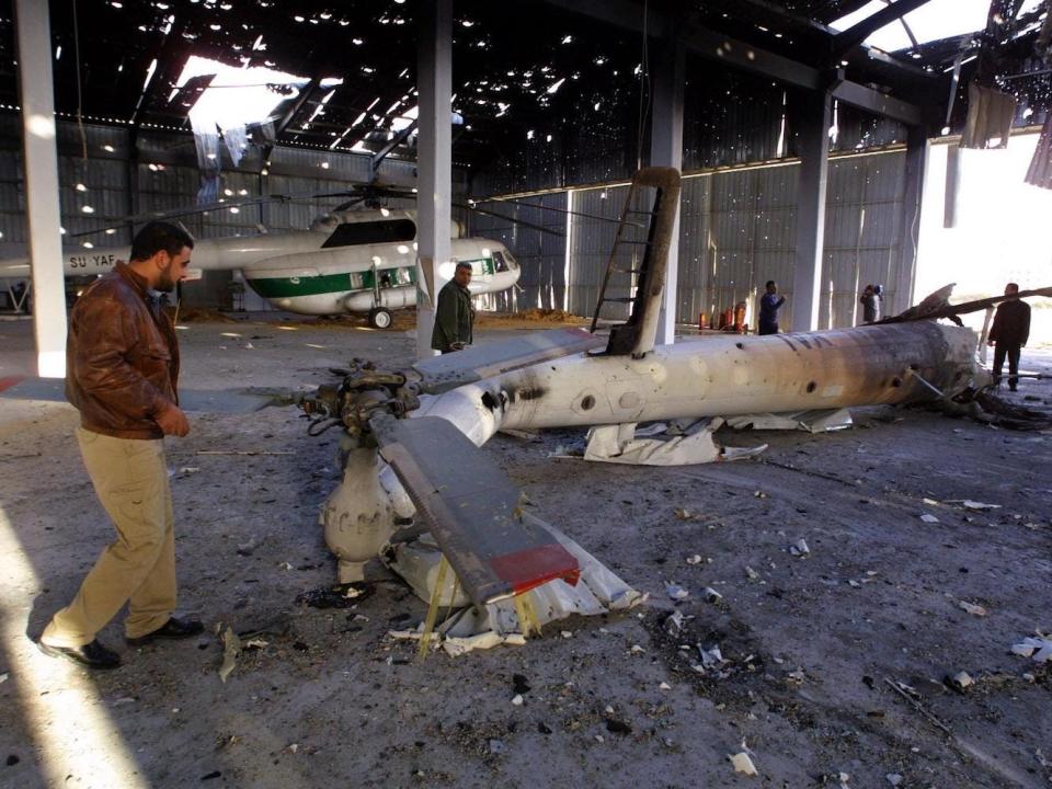 Palestinian policemen inspect one of the helicopters destroyed during Israeli army attack in 2001.